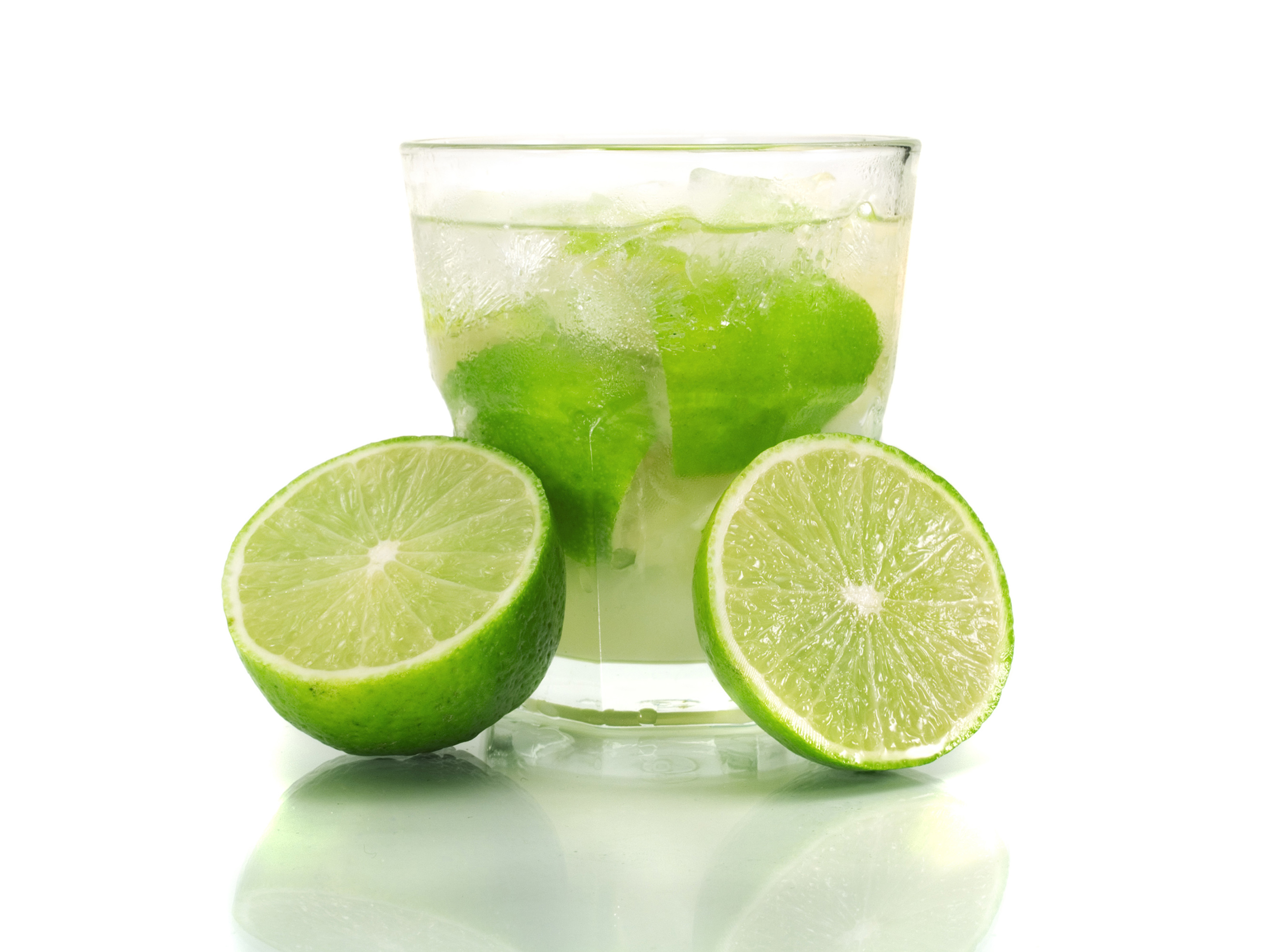 Cóctel caipirinha servido en un vaso con una lima a cada lado